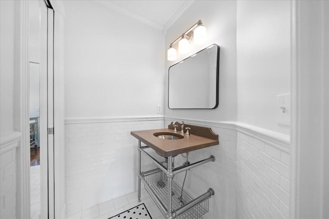 bathroom with crown molding, a sink, and a wainscoted wall