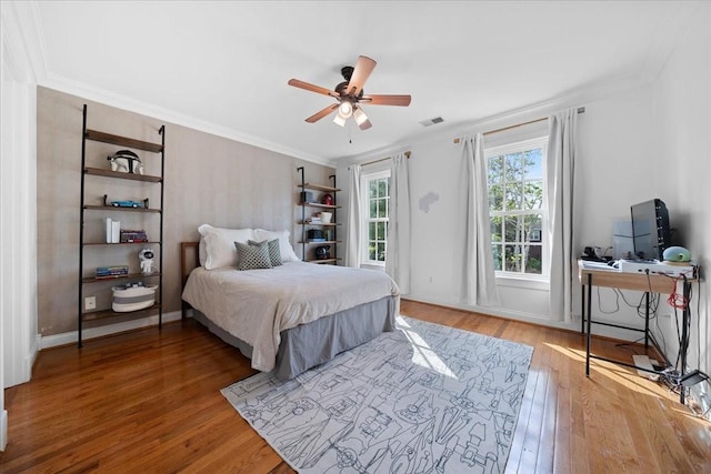 bedroom with baseboards, ornamental molding, wood finished floors, and visible vents