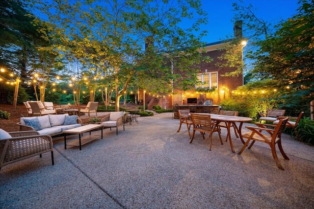 patio at night featuring outdoor dining area, outdoor lounge area, and an outdoor kitchen