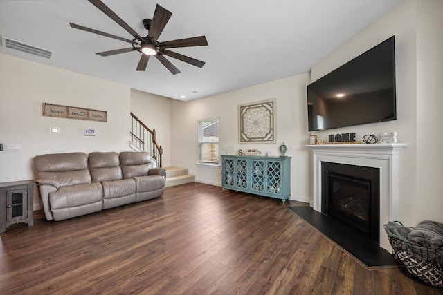 living area with visible vents, ceiling fan, wood finished floors, and stairway