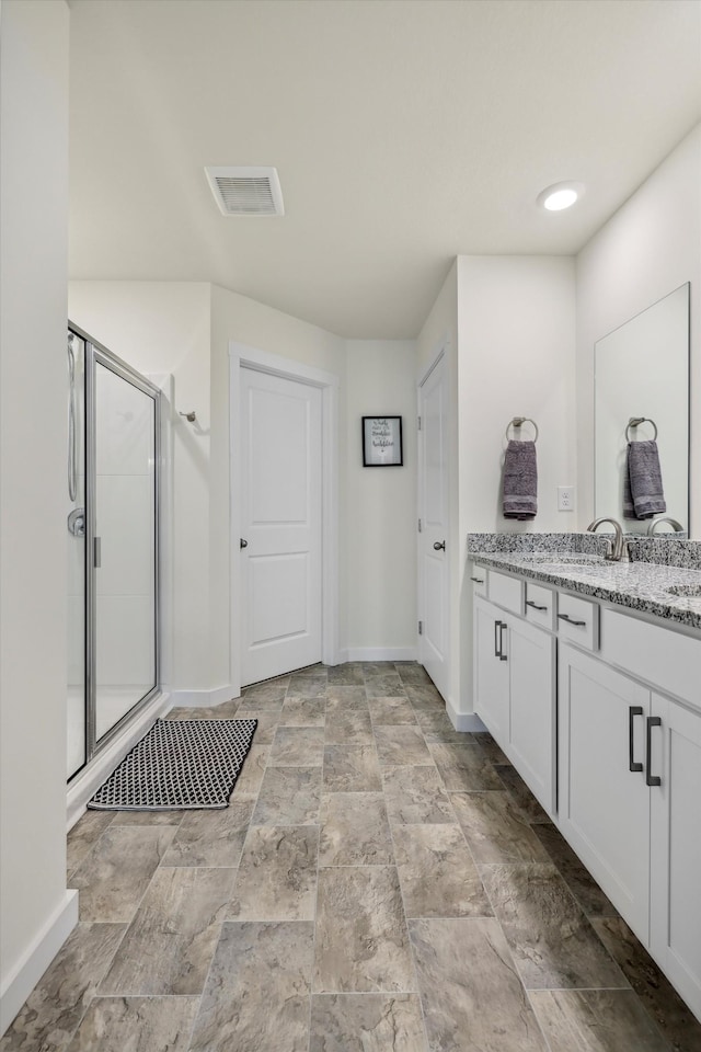 interior space featuring vanity, stone finish floor, baseboards, visible vents, and a stall shower