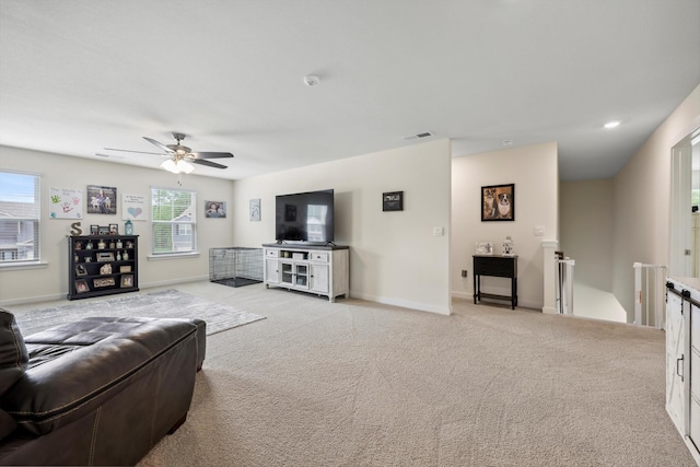 living area with light colored carpet, baseboards, ceiling fan, and visible vents