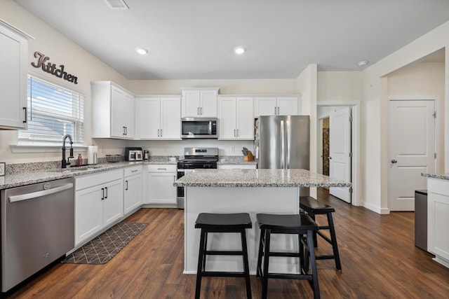 kitchen with a sink, a breakfast bar, stainless steel appliances, and white cabinetry