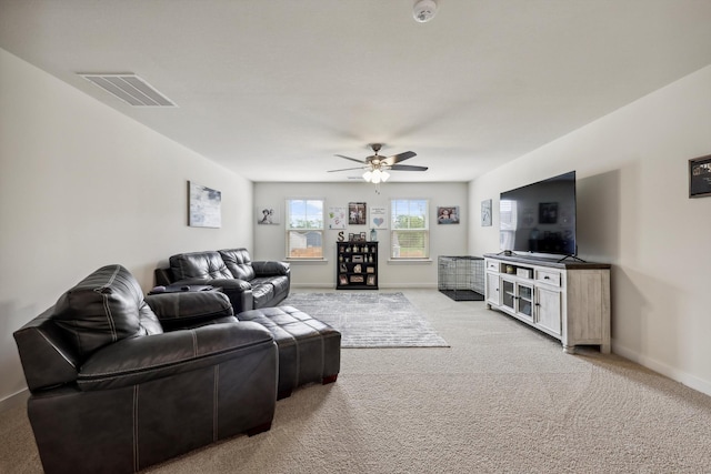 living area with baseboards, ceiling fan, light colored carpet, and visible vents
