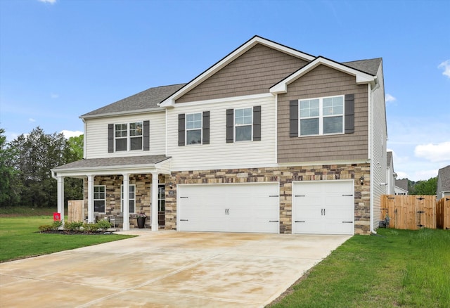 craftsman house featuring driveway, fence, a front lawn, an attached garage, and stone siding
