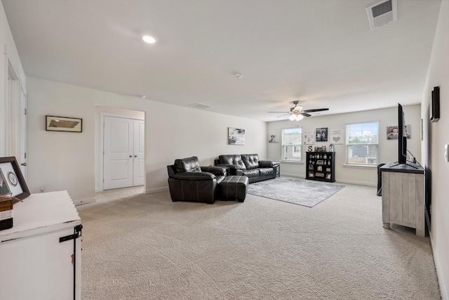 living area with baseboards, light carpet, a ceiling fan, and visible vents