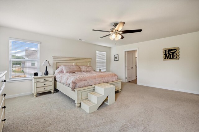 bedroom featuring baseboards, visible vents, light carpet, and ceiling fan