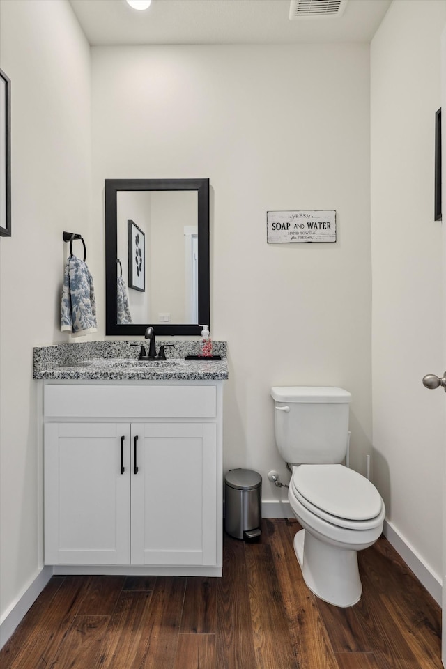 bathroom featuring visible vents, wood finished floors, vanity, baseboards, and toilet