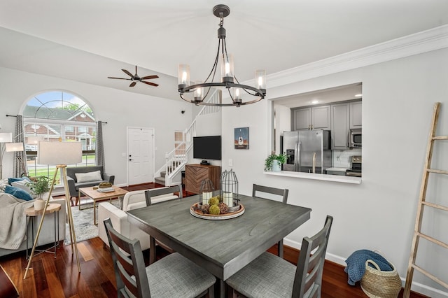 dining space featuring crown molding, dark wood-style flooring, ceiling fan with notable chandelier, and stairs