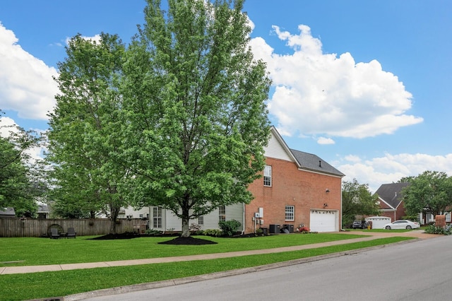 view of side of home with a lawn, brick siding, central AC, fence, and an attached garage