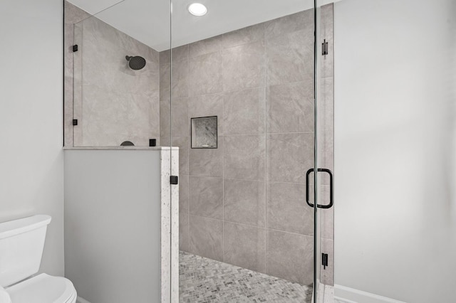 full bath with baseboards, toilet, and a shower stall
