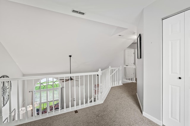 hall with visible vents, baseboards, an upstairs landing, carpet, and lofted ceiling