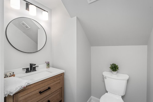 bathroom with visible vents, vaulted ceiling, vanity, baseboards, and toilet