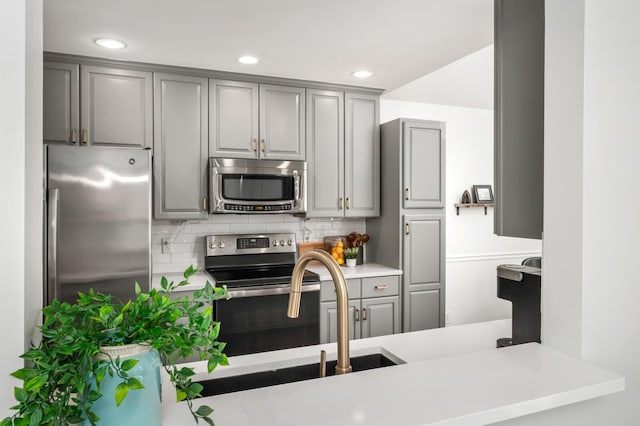 kitchen with appliances with stainless steel finishes, light countertops, gray cabinets, recessed lighting, and decorative backsplash