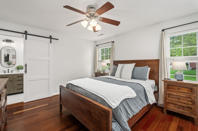 bedroom with dark wood finished floors, a barn door, a sink, and visible vents
