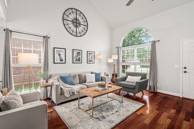 living room with a ceiling fan, high vaulted ceiling, dark wood finished floors, and baseboards