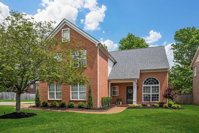 traditional-style house featuring fence, brick siding, and a front yard