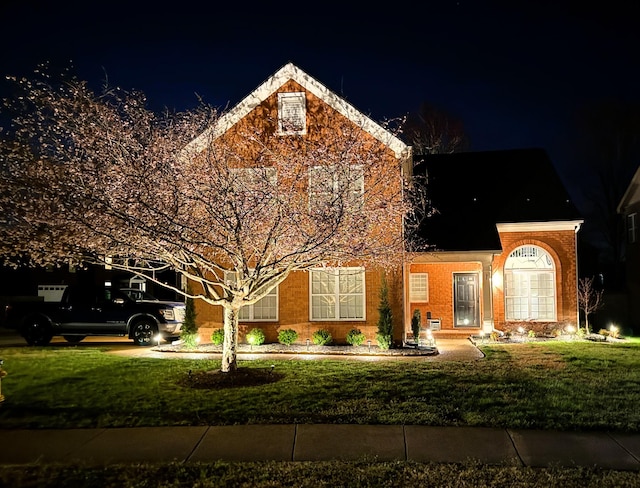 view of front of property featuring a lawn and brick siding