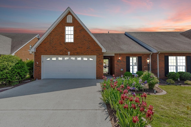 traditional home featuring a garage, roof with shingles, brick siding, a lawn, and driveway