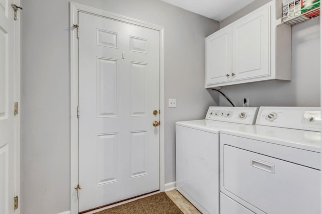 clothes washing area with baseboards, washing machine and dryer, and cabinet space