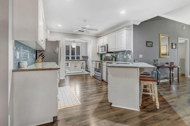 kitchen featuring crown molding, a peninsula, white cabinets, a sink, and appliances with stainless steel finishes