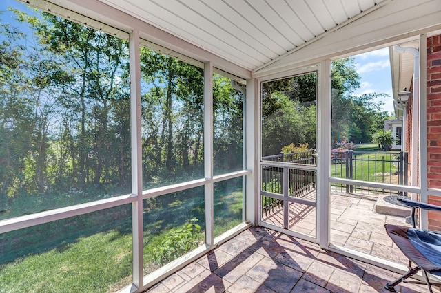 unfurnished sunroom featuring stone tile floors and lofted ceiling