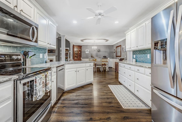kitchen with a sink, white cabinetry, a peninsula, and stainless steel appliances