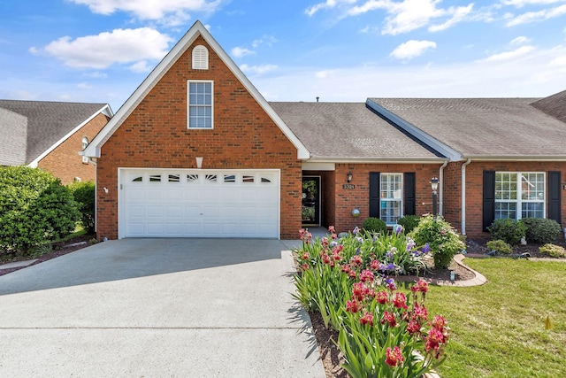view of front of house featuring a shingled roof, a front lawn, brick siding, a garage, and driveway