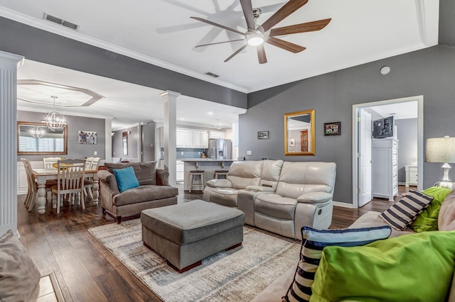living room with decorative columns, hardwood / wood-style flooring, visible vents, and ceiling fan with notable chandelier