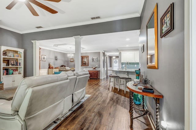 living area with crown molding, ceiling fan, visible vents, and dark wood finished floors