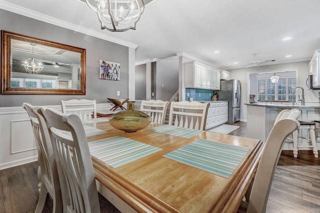 dining space with recessed lighting, ornamental molding, ceiling fan with notable chandelier, and dark wood-style floors