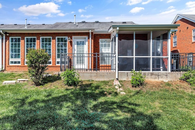 back of property with roof with shingles, a sunroom, a yard, and brick siding