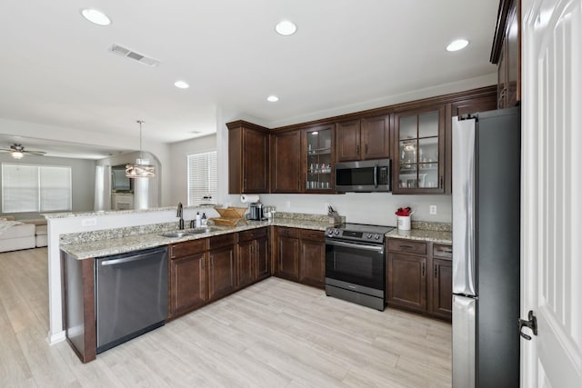 kitchen with visible vents, a peninsula, open floor plan, a sink, and stainless steel appliances
