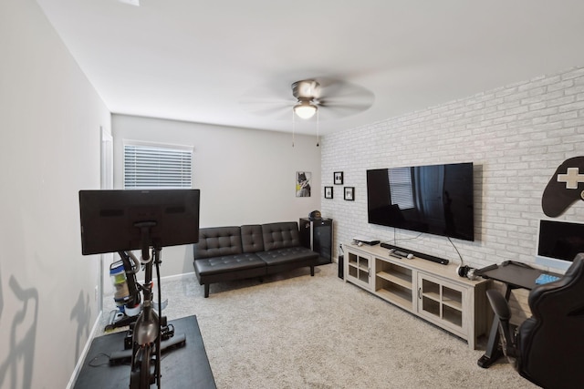 living area with carpet flooring, a ceiling fan, baseboards, and brick wall