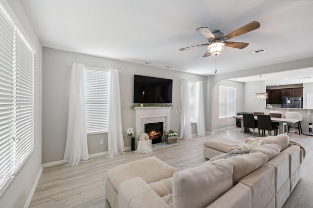 living area featuring a wealth of natural light, ceiling fan, light wood-style flooring, and visible vents