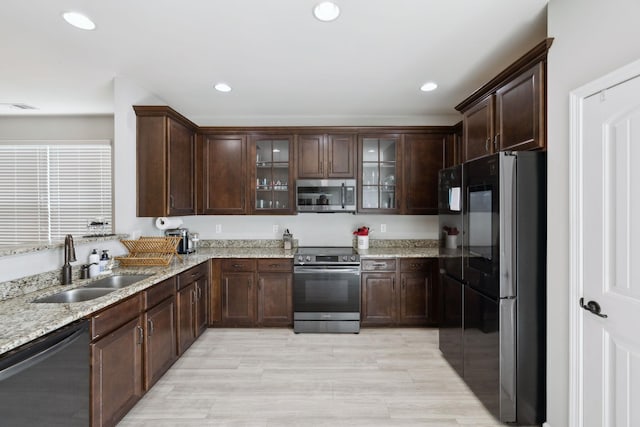 kitchen with dark brown cabinetry, light stone countertops, a sink, stainless steel appliances, and visible vents