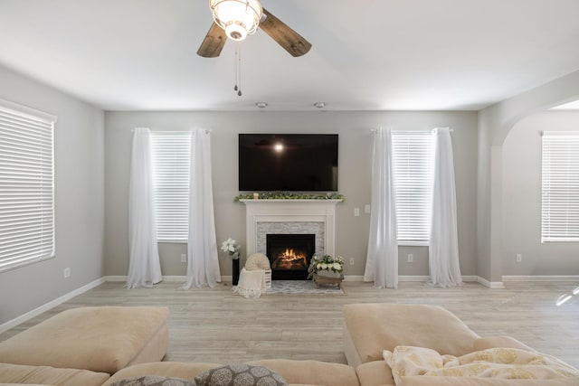 living room with a ceiling fan, baseboards, wood finished floors, and a fireplace