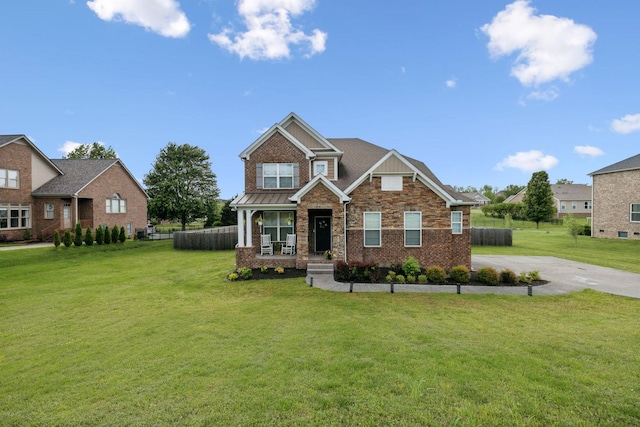 craftsman house featuring brick siding, a front lawn, covered porch, and driveway
