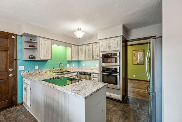 kitchen with open shelves, a sink, a textured ceiling, stainless steel appliances, and a peninsula