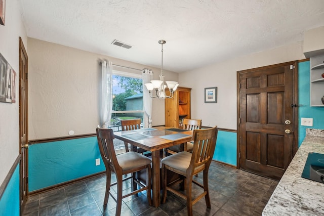 dining area with a textured ceiling, baseboards, a chandelier, and visible vents