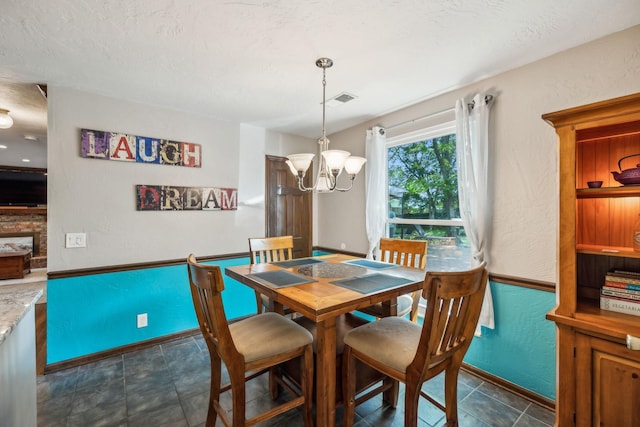 dining room with an inviting chandelier, baseboards, a textured wall, and visible vents