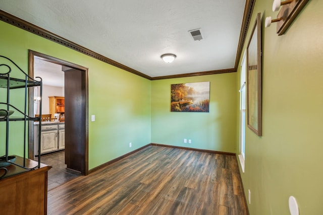 empty room featuring a textured ceiling, visible vents, crown molding, baseboards, and dark wood-type flooring
