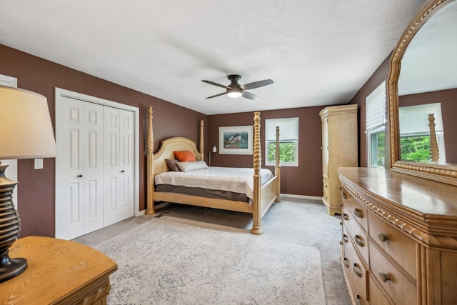 bedroom featuring light colored carpet, a ceiling fan, baseboards, and a closet