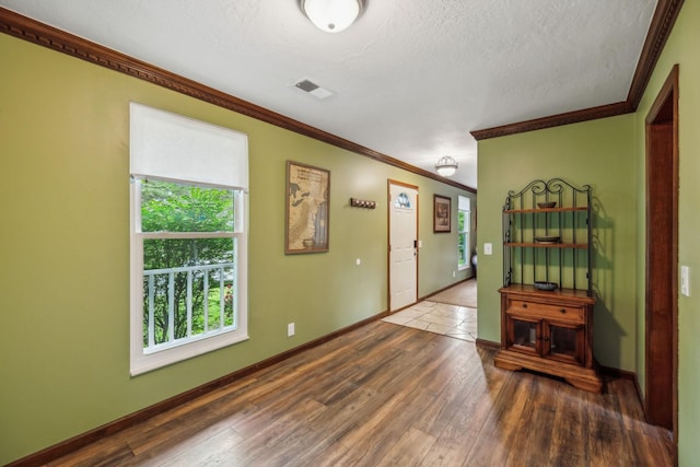 entrance foyer with baseboards, ornamental molding, hardwood / wood-style flooring, and visible vents