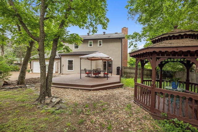 back of house featuring a gazebo, a chimney, fence, and a deck