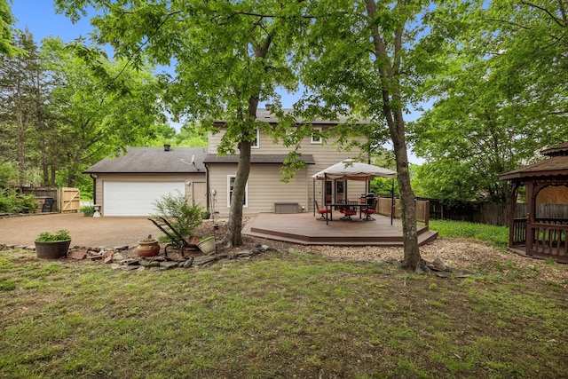 back of property featuring fence, a wooden deck, a gazebo, and driveway