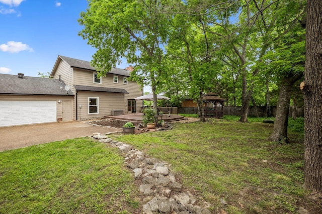 view of yard with concrete driveway, a gazebo, fence, and a garage