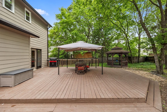 wooden terrace with a fenced backyard, outdoor dining space, a gazebo, and grilling area