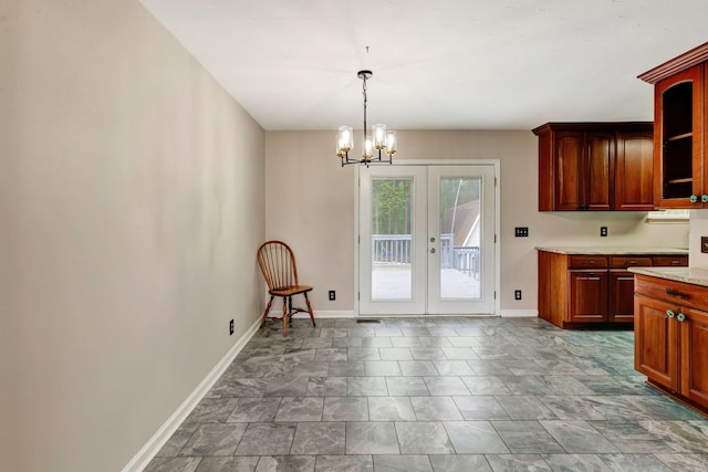 kitchen featuring baseboards, light countertops, a chandelier, french doors, and hanging light fixtures