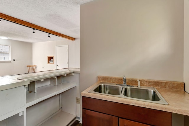 kitchen featuring track lighting, a sink, a textured ceiling, and light countertops